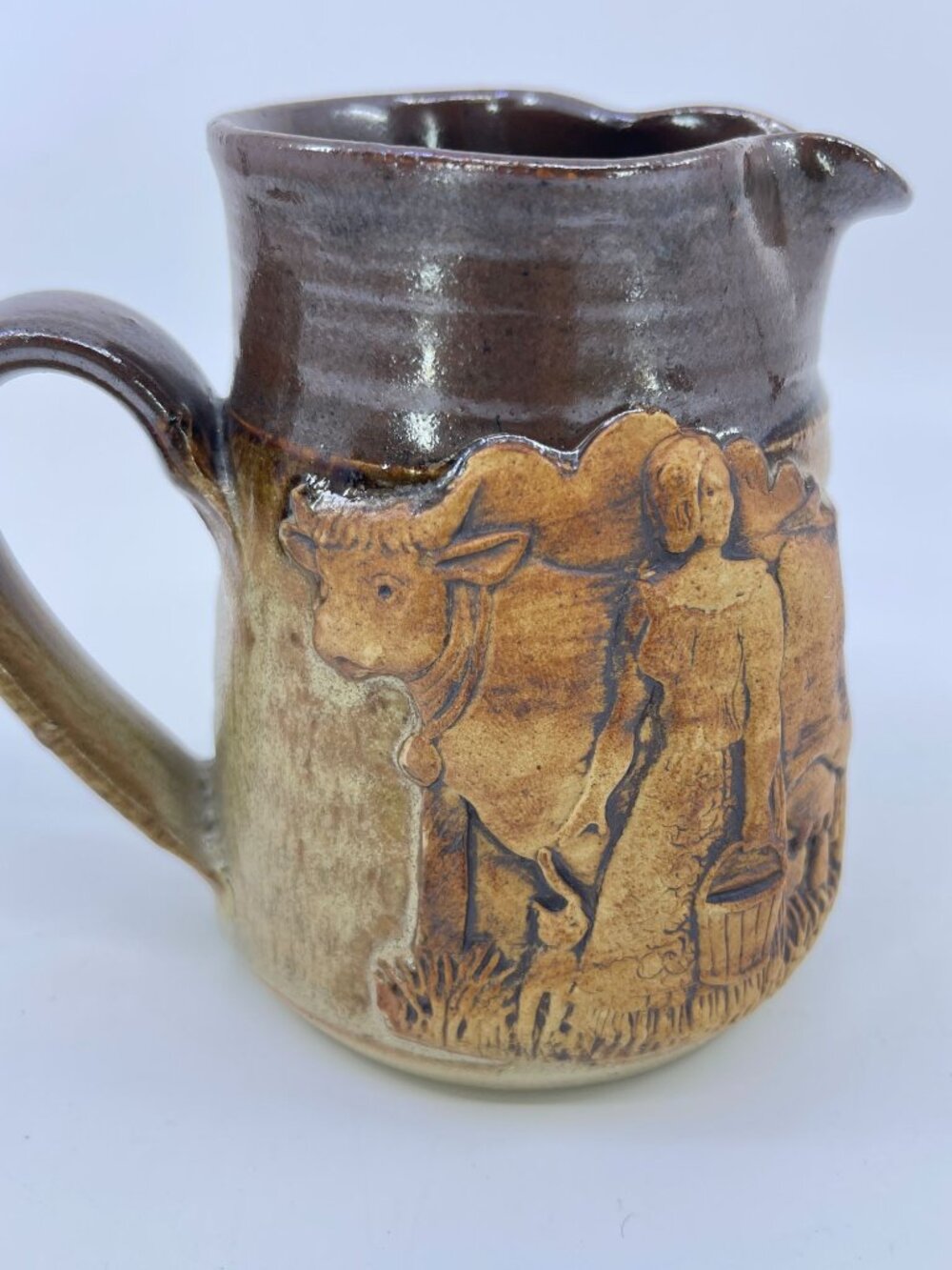 vintage handcrafted pottery creamer with rustic cow & milkmaid relief design